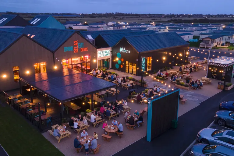 Evening entertainment venue with outdoor seating lit by festoon lights